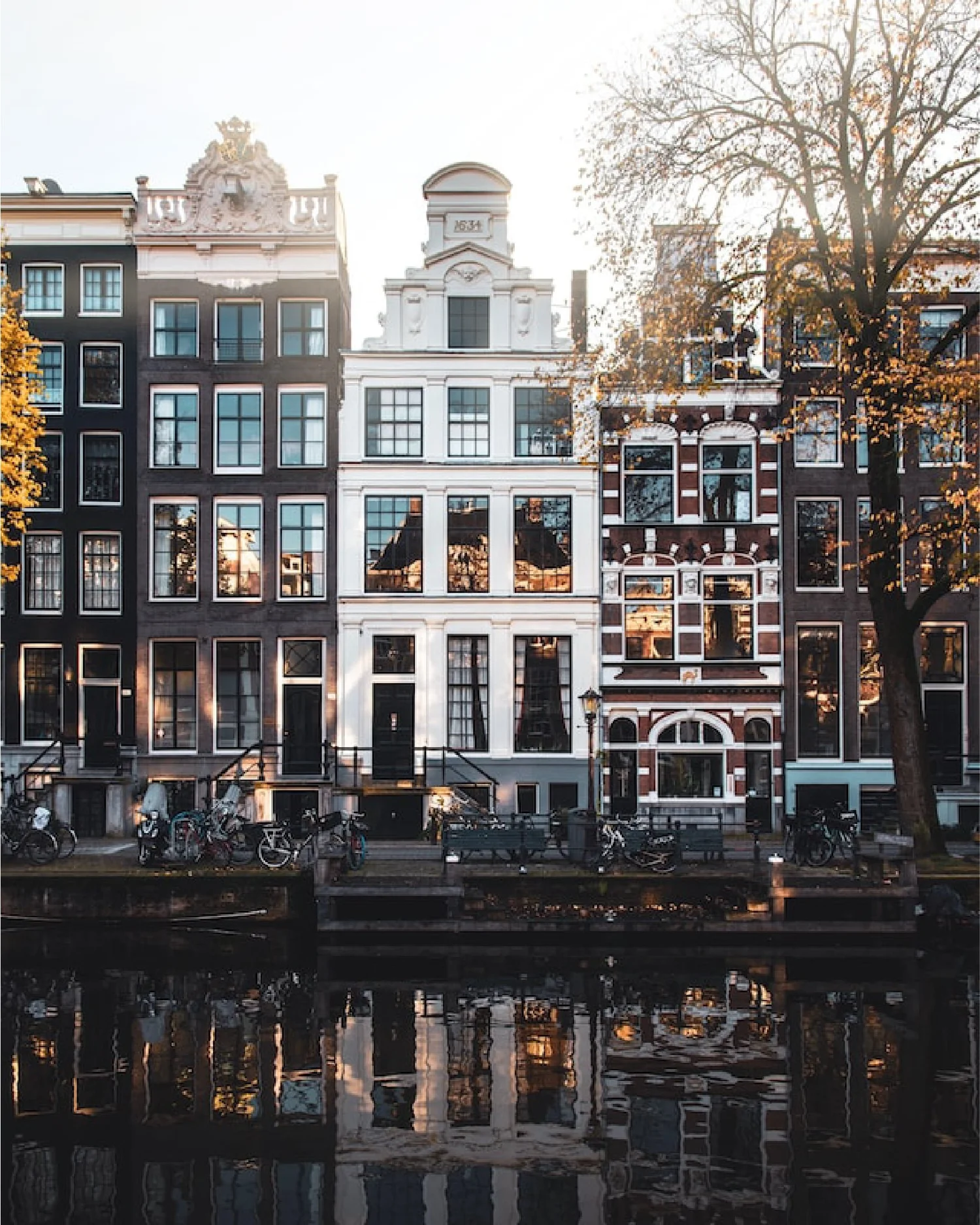 Klassieke Amsterdamse grachtenpanden weerspiegeld in het water — aankoopmakelaar Amsterdam